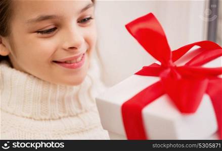 childhood, birthday, holidays and people concept - happy beautiful girl with christmas gift box at home. happy beautiful girl with christmas gift at home