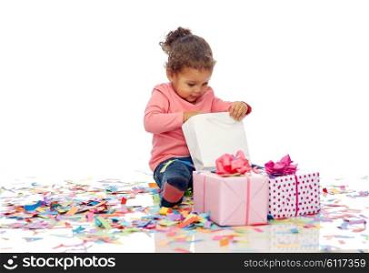 childhood, birthday, party, holidays and people concept - happy smiling little african american baby girl with gift boxes and confetti playing with shopping bag sitting on floor