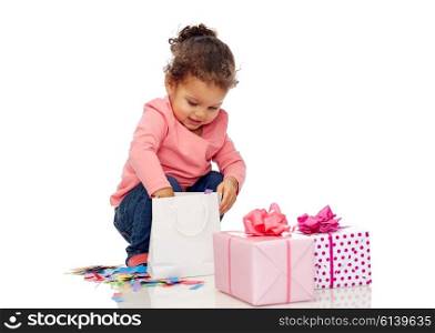 childhood, birthday, party, holidays and people concept - happy smiling little african american baby girl with gift boxes playing with confetti and shopping bag