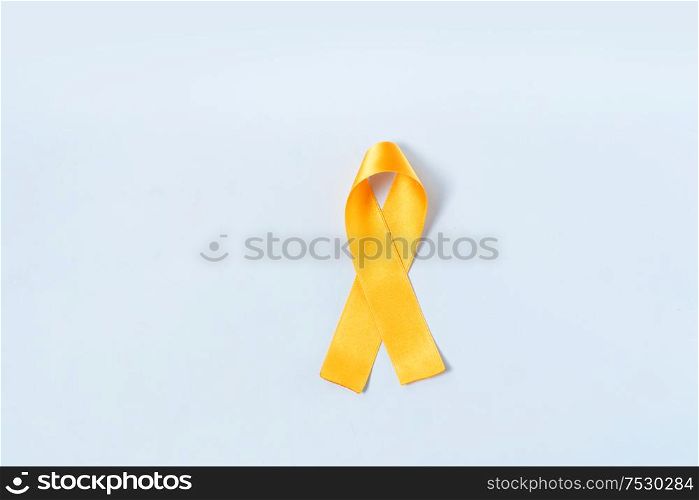 Childhood Cancer Awareness Yellow Ribbon and stethoscope on blue background with copy space. Childhood Cancer Day February, 15. Childhood Cancer Awareness concept
