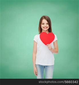 childhood, charity, education, love and people concept - smiling little girl sitting with red heart cutout over green blackboard background