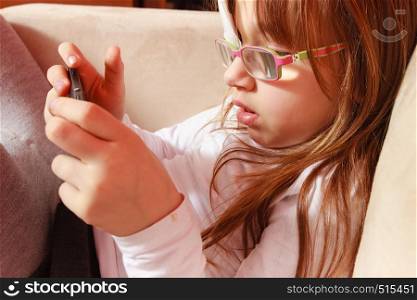 Childhood, childcare, being polite concept. Little toddler girl with bandage on eye playing games on smartphone. Toddler girl with bandage on eye playing games