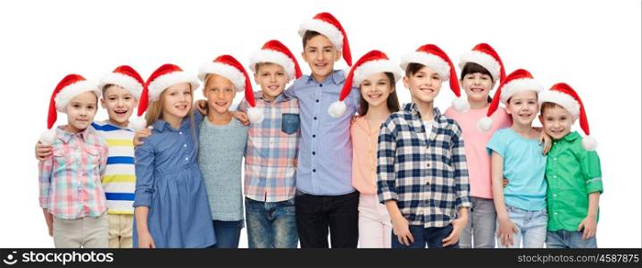 childhood, christmas, holidays and people concept - happy smiling children in santa hats hugging