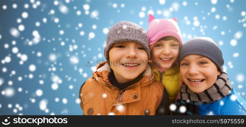 childhood, christmas, winter, friendship and people concept - group of happy kids hugging over snow background