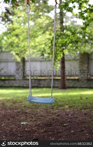 childhood concept - empty wooden swing hanging in summer garden. empty wooden swing hanging in summer garden