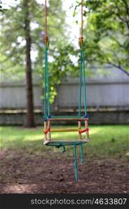 childhood concept - empty wooden swing hanging in summer garden. empty wooden swing hanging in summer garden
