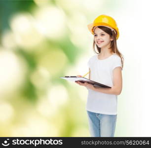 childhood, construction, architecture, building and people concept - smiling little girl in protective helmet with clipboard making notes