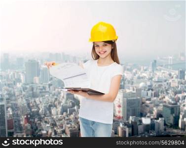 childhood, construction, architecture, building and people concept - smiling little girl in protective helmet with clipboard turning page