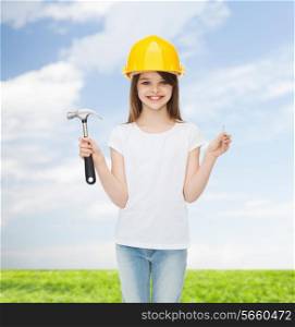 childhood, construction, architecture, building and people concept - smiling little girl in protective helmet with hammer