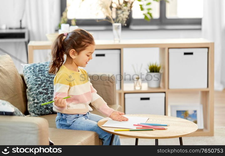 childhood, creativity and art concept - happy smiling little girl drawing with coloring pencils at home. little girl drawing with coloring pencils at home