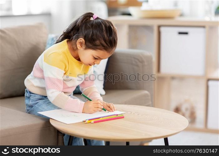 childhood, creativity and art concept - little girl drawing with coloring pencils at home. little girl drawing with coloring pencils at home