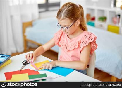 childhood, creativity and hobby concept - creative girl making greeting card and sticking patterned adhesive tape to color paper at home. creative girl making greeting card at home