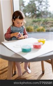 childhood, creativity and hobby concept - little baby girl with modeling clay playing at home. baby girl with modeling clay playing at home