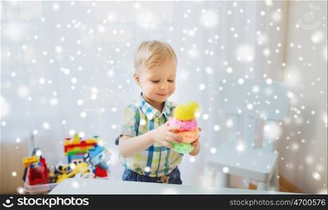 childhood, creativity, arts, activity and people concept - happy little baby boy playing with ball clay at home over snow