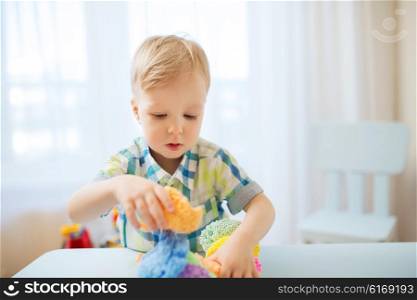 childhood, creativity, arts, activity and people concept - happy little baby boy playing with ball clay at home