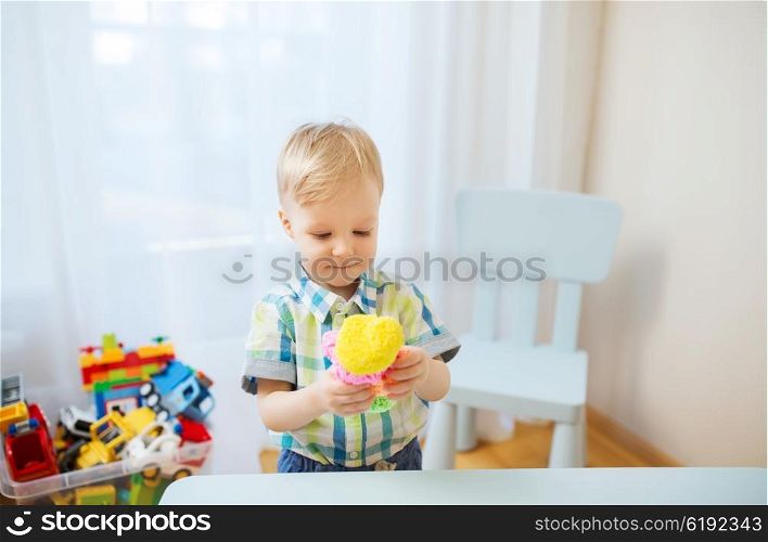 childhood, creativity, arts, activity and people concept - happy little baby boy playing with ball clay at home