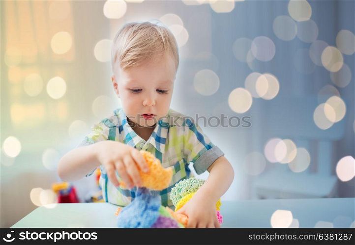 childhood, creativity, arts, activity and people concept - happy little baby boy playing with ball clay at home. happy little baby boy with ball clay at home