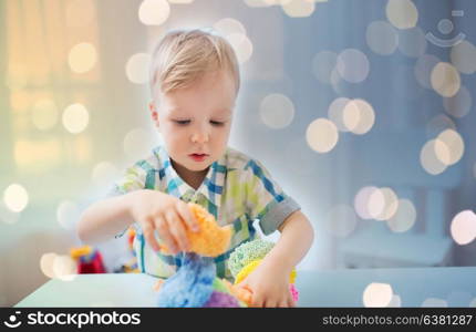 childhood, creativity, arts, activity and people concept - happy little baby boy playing with ball clay at home. happy little baby boy with ball clay at home