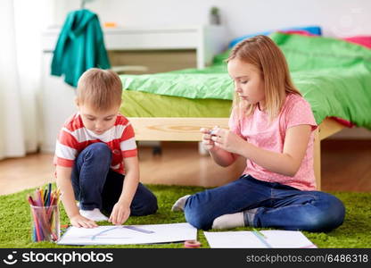 childhood, creativity, family and people concept - happy creative brother and sister with paper, crayons and adhesive tape making crafts at home. happy creative kids making crafts at home. happy creative kids making crafts at home