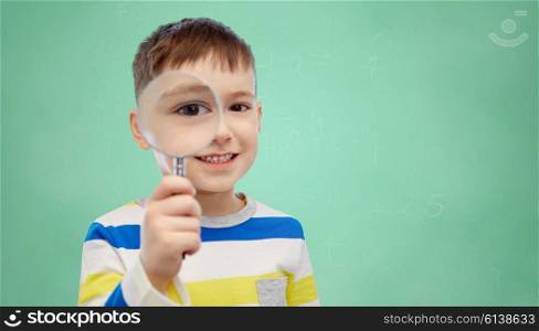 childhood, discovery, school, education and people concept - happy little boy looking through magnifying glass over green school chalk board background