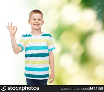 childhood, ecology, gesture and people concept - smiling little boy in casual clothes making OK gesture over green background