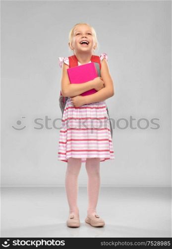 childhood, education and people concept - happy little student girl with school bag and book over grey background. happy little student girl with school bag and book