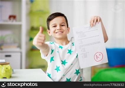 childhood, education and people concept - happy smiling boy holding school test with a grade showing thumbs up. happy smiling boy holding school test with a grade