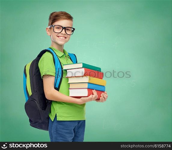 childhood, education and people concept - happy smiling student boy in eyeglasses with school bag and books over green school chalk board background