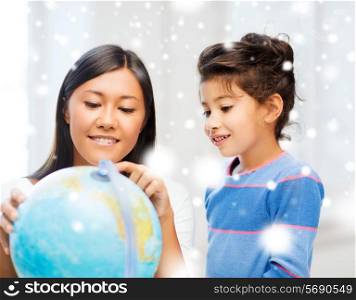 childhood, education, family and people concept - smiling little girl and mother or teacher with globe indoors