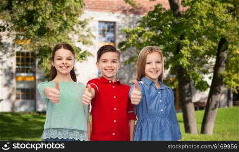 childhood, education, holidays, gesture and people concept - happy smiling boy and girls showing thumbs up over campus and summer park background