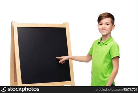 childhood, education, school, advertisement and people concept - happy smiling boy in green polo t-shirt with chalk and blank school blackboard