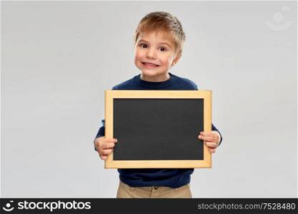 childhood, education, school, advertisement and people concept - little boy holding black blank chalk board. little boy holding black blank chalk board