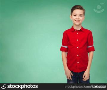 childhood, education, school and people concept - happy smiling boy in red shirt over green chalk board background