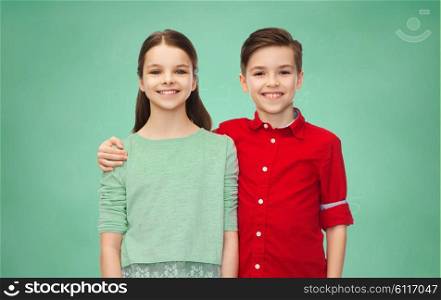 childhood, education, school, friendship and people concept - happy smiling boy and girl hugging over green chalk board background