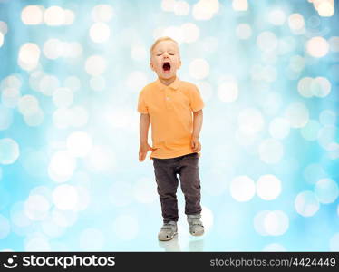 childhood, emotion, expression and people concept - happy little boy in casual clothes shouting, crying or sneezing over blue holidays lights background