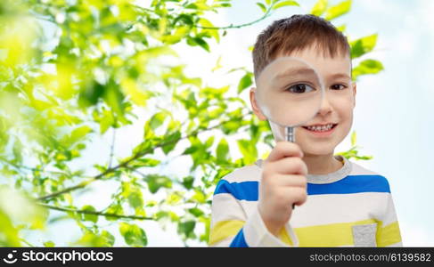 childhood, environment, ecology, discovery and people concept - happy little boy looking through magnifying glass over green natural background