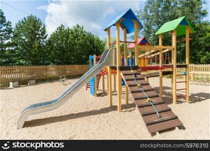 childhood, equipment and object concept - climbing frame with slide on playground outdoors at summer