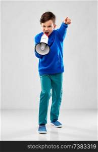 childhood, expressions and people concept - angry boy in blue hoodie speaking to megaphone over grey background. angry boy speaking to megaphone