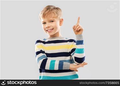 childhood, expressions and people concept - little boy in striped pullover pointing finger up over grey background. little boy in striped pullover pointing finger up
