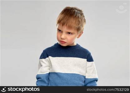 childhood, expressions and people concept - portrait of gloomy little boy in striped pullover over grey background. portrait of gloomy little boy in striped pullover