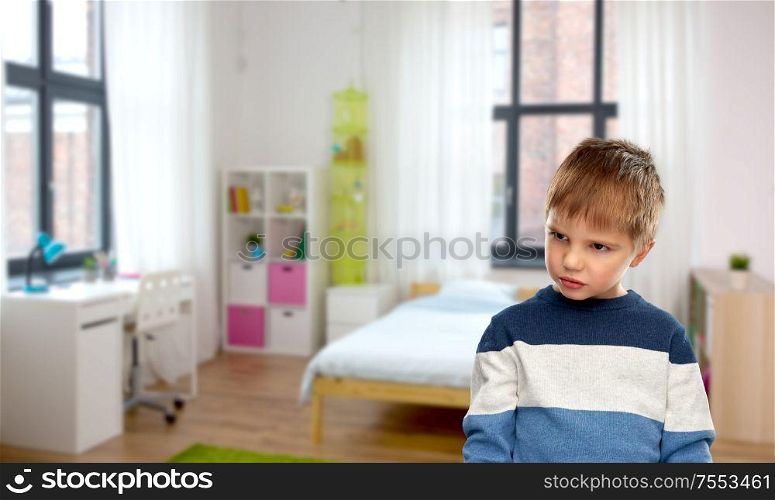 childhood, expressions and people concept - portrait of gloomy little boy in striped pullover over home room background. portrait of gloomy little boy at home