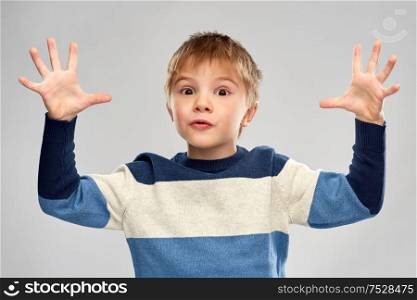 childhood, expressions and people concept - portrait of little boy in striped pullover playing over grey background. portrait of little boy in striped pullover playing