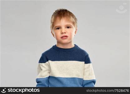 childhood, expressions and people concept - portrait of little boy in striped pullover over grey background. portrait of little boy in striped pullover