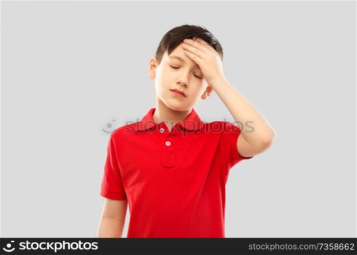 childhood, expressions and people concept - sick little boy in red polo t-shirt suffering from headache over grey background. sick boy in red t-shirt suffering from headache