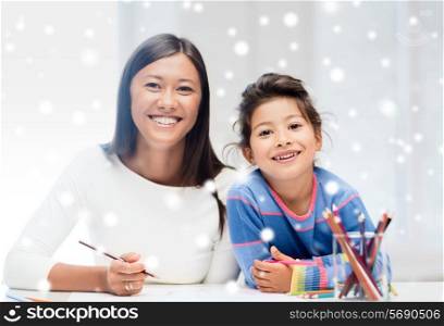 childhood, family, education and people concept - smiling little girl and mother or teacher drawing with coloring pencils indoors