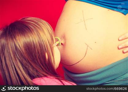 Childhood, family love concept. Toddler girl drawing on her mother big pregnant belly. Toddler girl drawing on mother pregnant belly