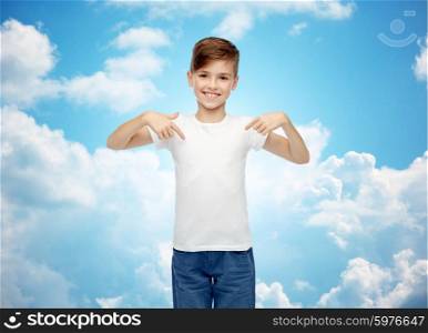 childhood, fashion, advertisement and people concept - happy boy in white t-shirt and jeans pointing finger to himself over blue sky and clouds background