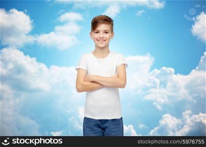 childhood, fashion, advertisement and people concept - happy boy in white t-shirt and jeans over blue sky and clouds background