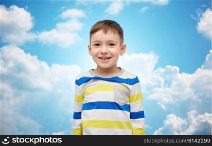 childhood, fashion, advertisement and people concept - happy smiling little boy over blue sky and clouds background