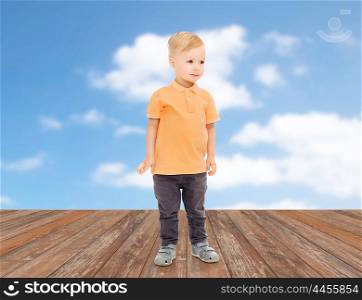 childhood, fashion and people concept - happy little boy in casual clothes over blue sky and clouds background